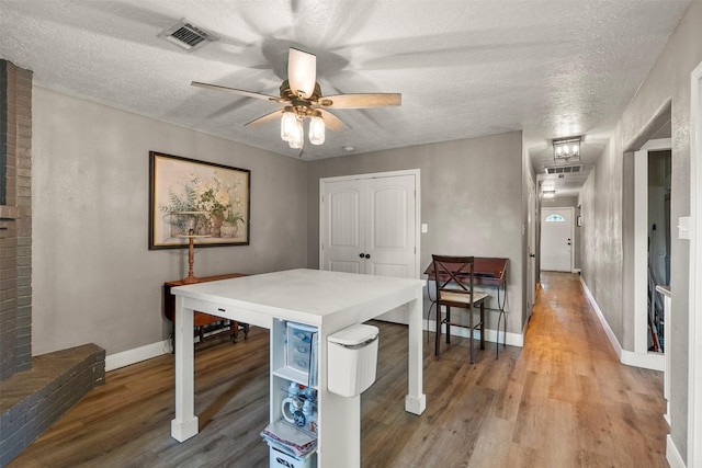 dining area with wood finished floors, a ceiling fan, baseboards, and a textured ceiling