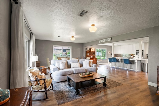 living area with wood finished floors, a textured ceiling, and baseboards