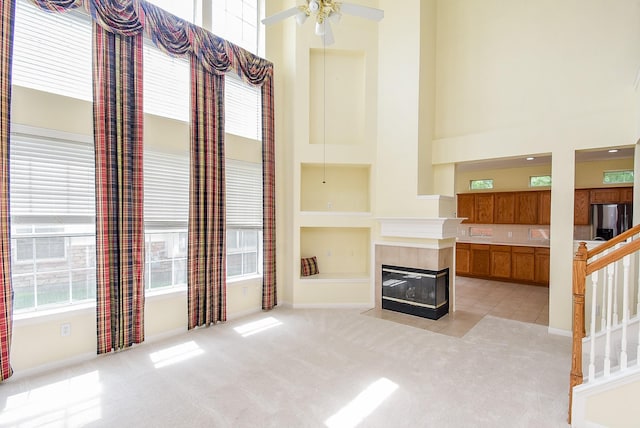 7218 Welshwood Ln, Sugar Land, TX 77479 - unfurnished living room with a towering ceiling, stairway, a tile fireplace, a ceiling fan, and built in features