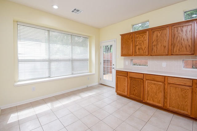 7218 Welshwood Ln, Sugar Land, TX 77479 - kitchen featuring brown cabinetry, light countertops, backsplash, light tile patterned flooring, and recessed lighting