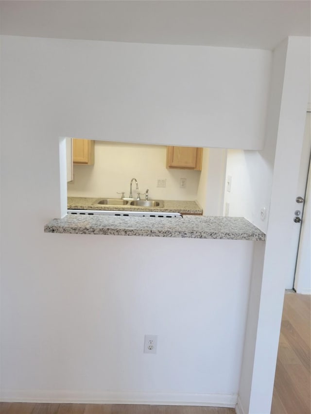 8425 Hearth Dr Unit 25, Houston, TX 77054 - kitchen featuring light brown cabinetry, a peninsula, a sink, wood finished floors, and light stone counters