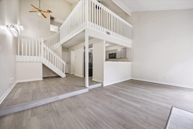 3148 Windchase Blvd Unit 442, Houston, TX 77082 - unfurnished living room with a ceiling fan, high vaulted ceiling, wood finished floors, stairway, and baseboards