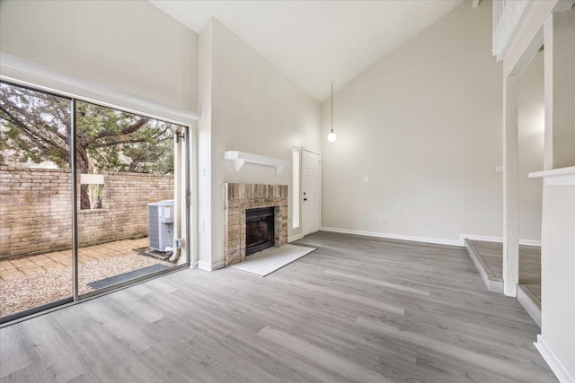 3148 Windchase Blvd Unit 442, Houston, TX 77082 - unfurnished living room featuring high vaulted ceiling, a fireplace, wood finished floors, and baseboards