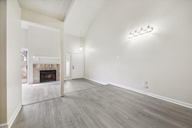 3148 Windchase Blvd Unit 442, Houston, TX 77082 - unfurnished living room featuring baseboards, wood finished floors, high vaulted ceiling, and a fireplace