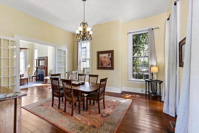 1427 Winnie St, Galveston, TX 77550 - dining area featuring a chandelier, wood-type flooring, baseboards, and a wood stove