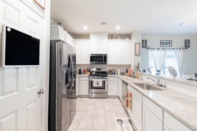 26019 Babe Ruth Dr, Splendora, TX 77372 - kitchen featuring stainless steel appliances, a sink, white cabinetry, light stone counters, and recessed lighting