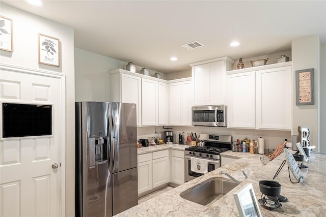 26019 Babe Ruth Dr, Splendora, TX 77372 - kitchen with appliances with stainless steel finishes, a sink, light stone countertops, white cabinets, and recessed lighting