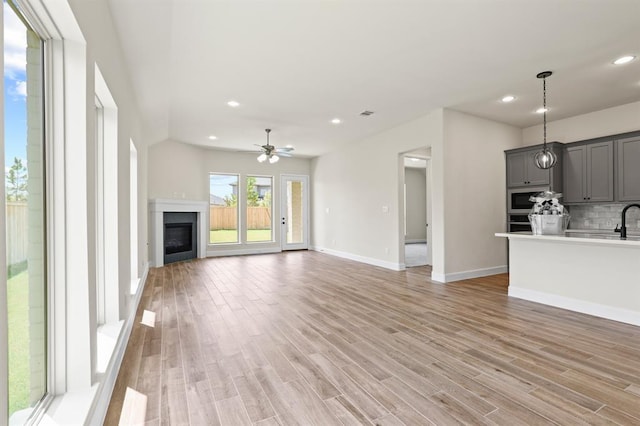 18511 Wolf Mountain Ln, Cypress, TX 77433 - unfurnished living room featuring a ceiling fan, recessed lighting, light wood-type flooring, baseboards, and a glass covered fireplace