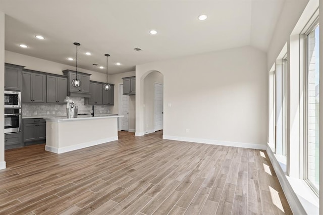 18511 Wolf Mountain Ln, Cypress, TX 77433 - kitchen featuring stainless steel appliances, gray cabinets, backsplash, open floor plan, and light countertops