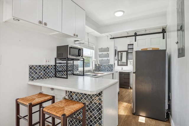 1350 23rd St, San Leon, TX 77539 - kitchen featuring appliances with stainless steel finishes, a peninsula, wood finished floors, backsplash, and light countertops