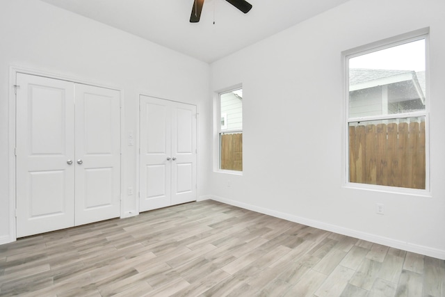 3309 Shelby Cir, Houston, TX 77051 - unfurnished bedroom featuring two closets, light wood-type flooring, baseboards, and a ceiling fan