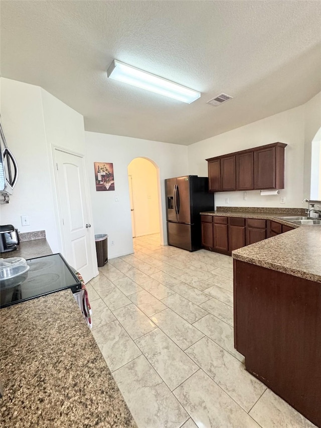 5723 Treasure Cove Rd, Cove, TX 77523 - kitchen with refrigerator with ice dispenser, a sink, arched walkways, a textured ceiling, and electric stove