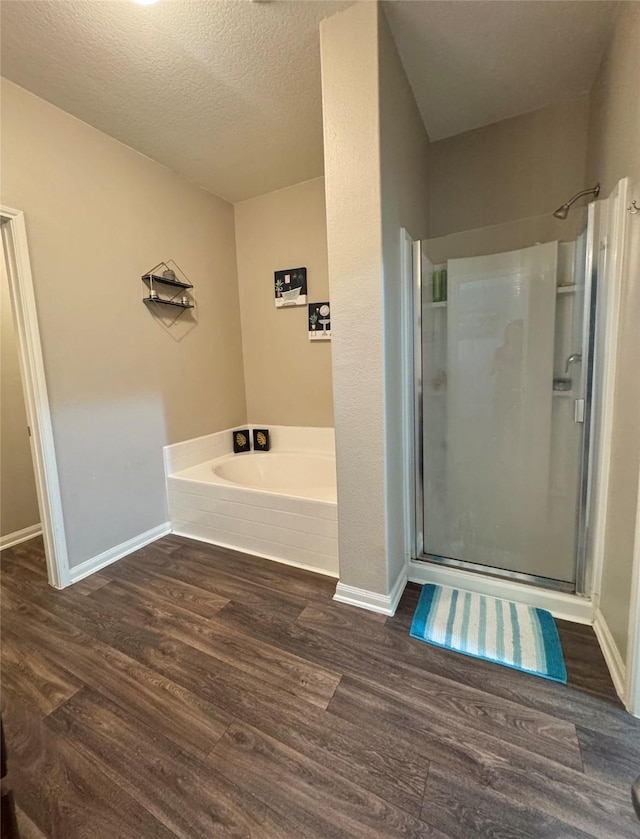 5723 Treasure Cove Rd, Cove, TX 77523 - bathroom featuring a shower stall, wood finished floors, a bath, baseboards, and a textured ceiling
