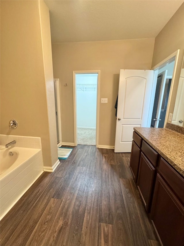 5723 Treasure Cove Rd, Cove, TX 77523 - bathroom featuring wood finished floors, a garden tub, a shower stall, vanity, and baseboards
