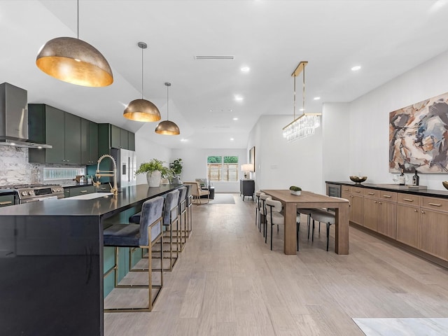 1208 Curtin St, Houston, TX 77018 - kitchen with wall chimney exhaust hood, dark countertops, light wood-style flooring, tasteful backsplash, and recessed lighting