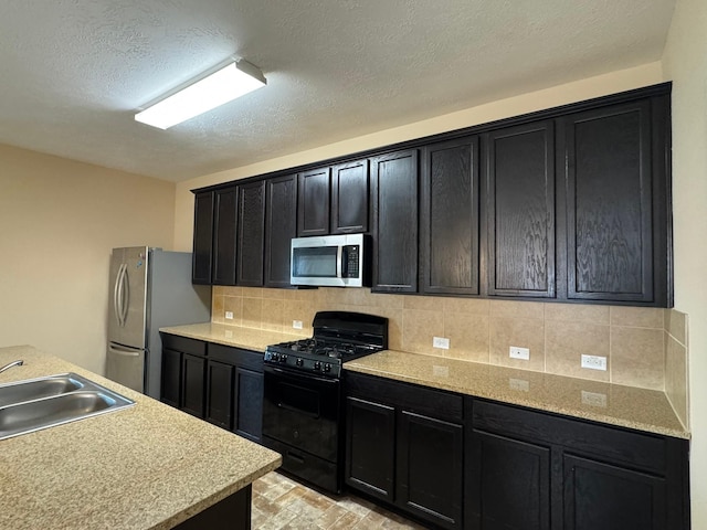 42 Blisten Spring Dr, Manvel, TX 77578 - kitchen with appliances with stainless steel finishes, a sink, dark cabinets, light countertops, and tasteful backsplash