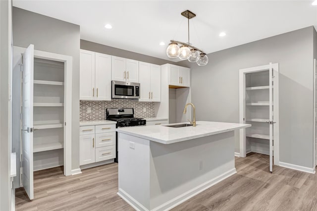 6814 Dumble St, Houston, TX 77021 - kitchen with stainless steel appliances, a sink, light wood-type flooring, white cabinets, and recessed lighting