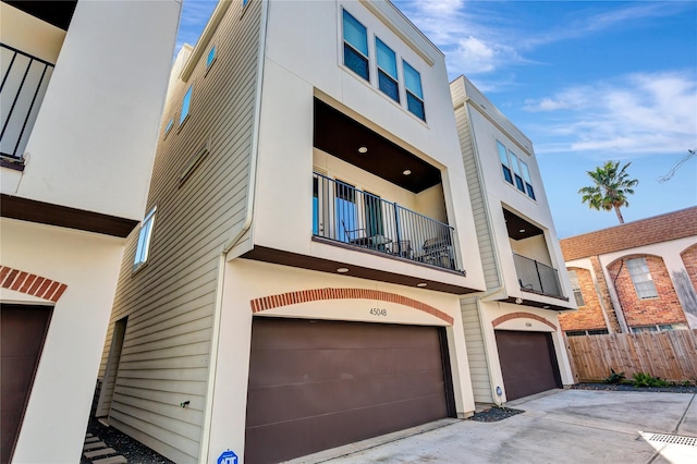 4504 Mount Vernon St Unit A, Houston, TX 77006 - view of front of house with an attached garage, fence, a balcony, and stucco siding