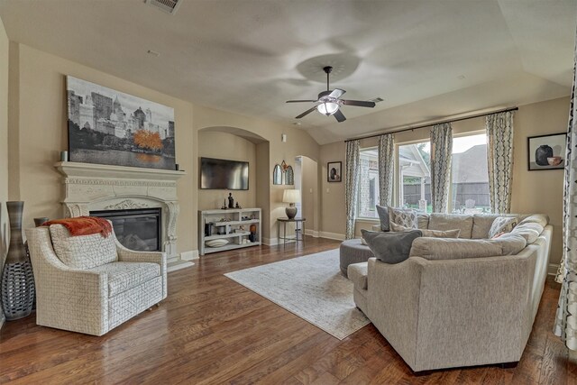 21514 Fairhaven Creek Dr, Cypress, TX 77433 - living room featuring arched walkways, a ceiling fan, a glass covered fireplace, wood finished floors, and vaulted ceiling