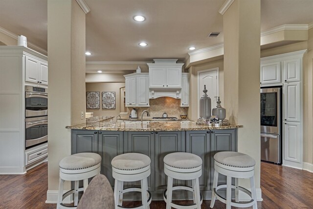 21514 Fairhaven Creek Dr, Cypress, TX 77433 - kitchen featuring double oven, white cabinetry, dark wood-type flooring, light stone countertops, and backsplash