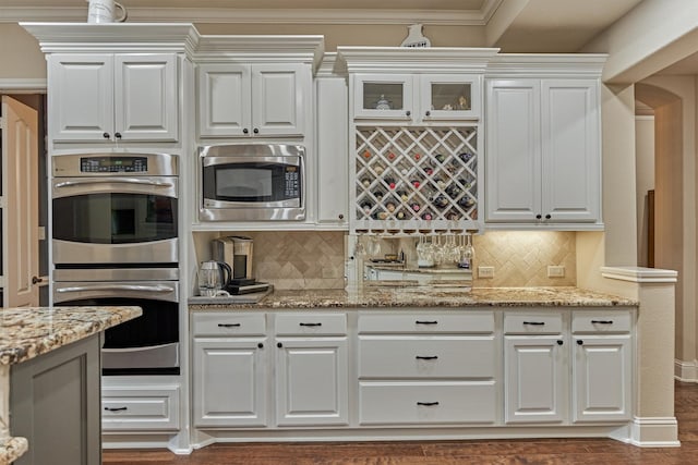 21514 Fairhaven Creek Dr, Cypress, TX 77433 - kitchen featuring appliances with stainless steel finishes, white cabinetry, tasteful backsplash, light stone countertops, and glass insert cabinets
