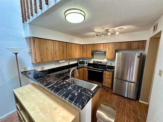 2611 Grants Lake Blvd Unit 237, Sugar Land, TX 77479 - kitchen featuring appliances with stainless steel finishes, a sink, wood finish floors, brown cabinetry, and a textured ceiling