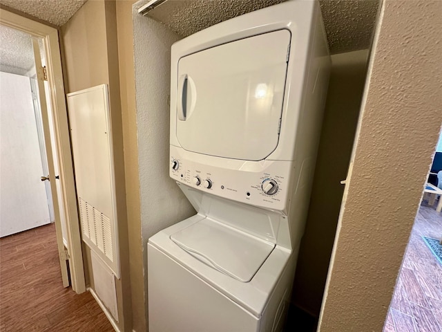 2611 Grants Lake Blvd Unit 237, Sugar Land, TX 77479 - washroom featuring stacked washer and clothes dryer, a textured wall, wood finished floors, and a textured ceiling