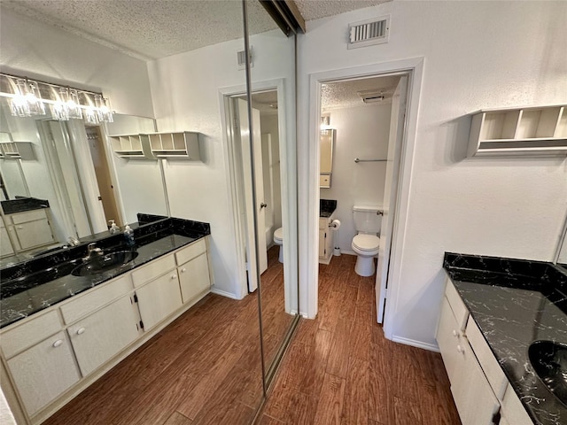 2611 Grants Lake Blvd Unit 237, Sugar Land, TX 77479 - bathroom featuring toilet, a textured ceiling, wood finished floors, and vanity