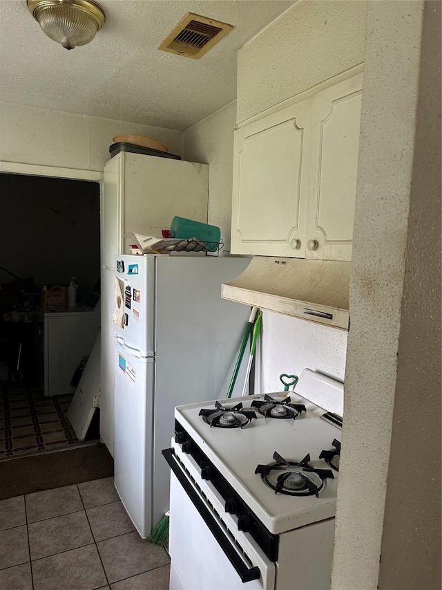 7722 Claiborne St, Houston, TX 77016 - kitchen with white gas range, ventilation hood, light tile patterned flooring, and white cabinetry