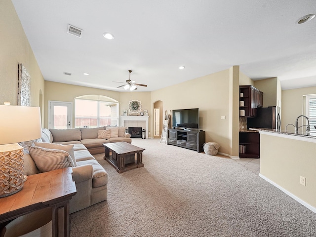 29954 Spring Creek Ln, Brookshire, TX 77423 - living area featuring light carpet, ceiling fan, arched walkways, a tile fireplace, and baseboards