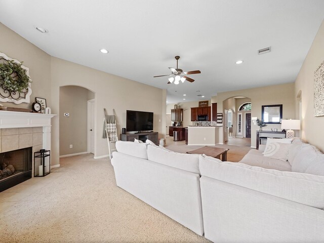 29954 Spring Creek Ln, Brookshire, TX 77423 - living room featuring arched walkways, a tile fireplace, ceiling fan, light colored carpet, and recessed lighting