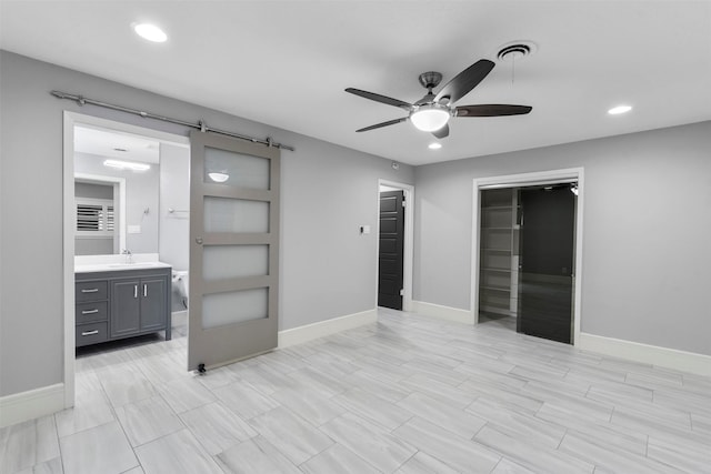 7727 Barberton Dr, Houston, TX 77036 - unfurnished bedroom with a barn door, a sink, recessed lighting, baseboards, and ensuite bath
