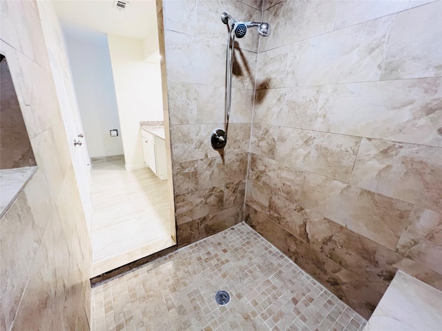 full bathroom with tiled shower and vanity