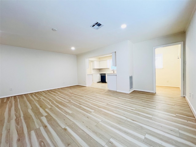 unfurnished living room featuring baseboards, light wood-style flooring, a sink, and recessed lighting