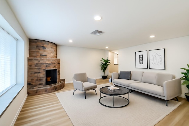 living room featuring light wood-type flooring, a large fireplace, recessed lighting, and baseboards