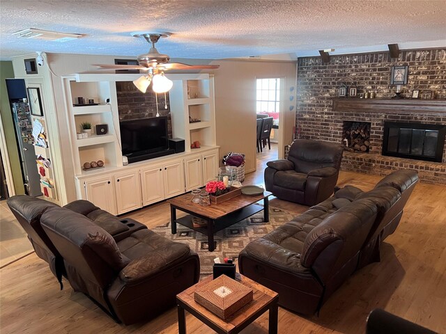 11615 Primwood Dr, Houston, TX 77070 - living room with a textured ceiling, a brick fireplace, ceiling fan, light wood-type flooring, and built in features