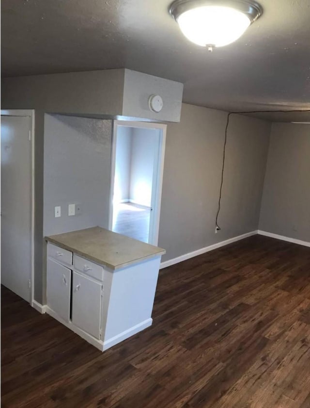 511 W Cleveland St, Alvin, TX 77511 - kitchen featuring dark wood-style flooring, baseboards, white cabinetry, and a peninsula