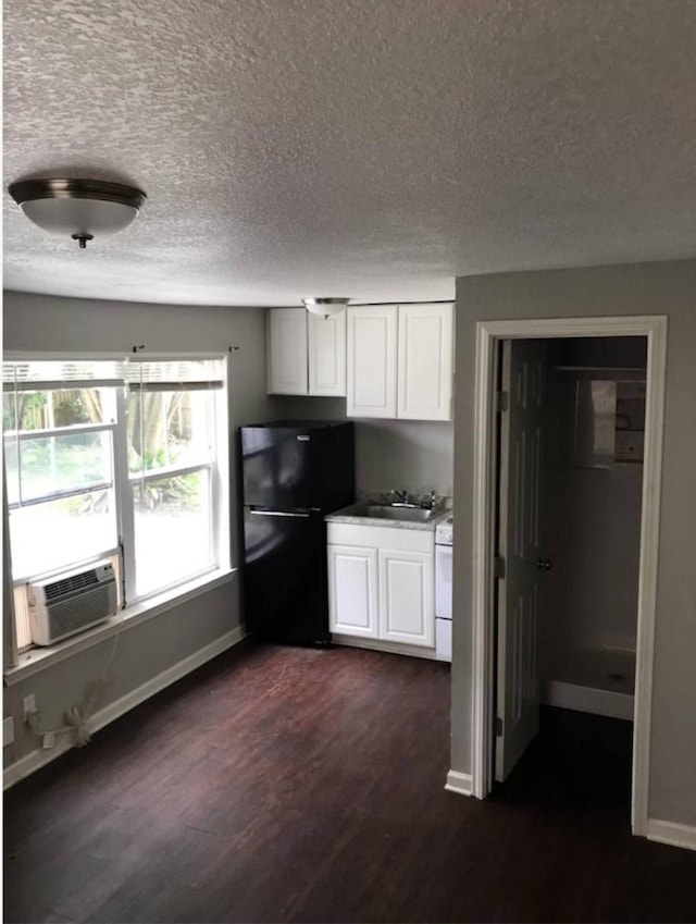 511 W Cleveland St, Alvin, TX 77511 - kitchen featuring freestanding refrigerator, dark wood finished floors, a sink, white cabinetry, and a textured ceiling