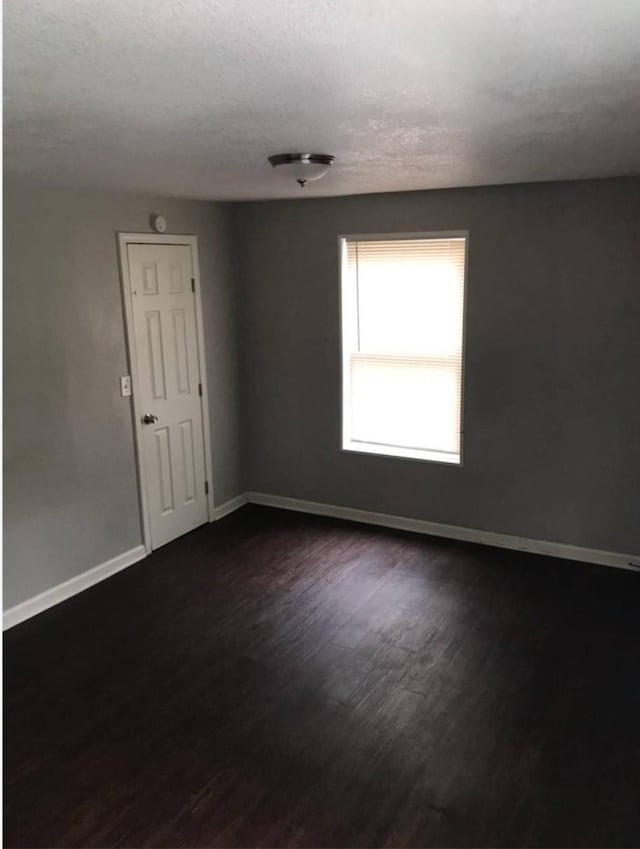 511 W Cleveland St, Alvin, TX 77511 - spare room featuring baseboards, dark wood finished floors, and a textured ceiling