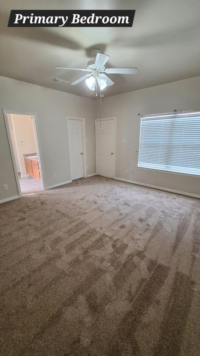 unfurnished bedroom featuring carpet, baseboards, connected bathroom, and ceiling fan