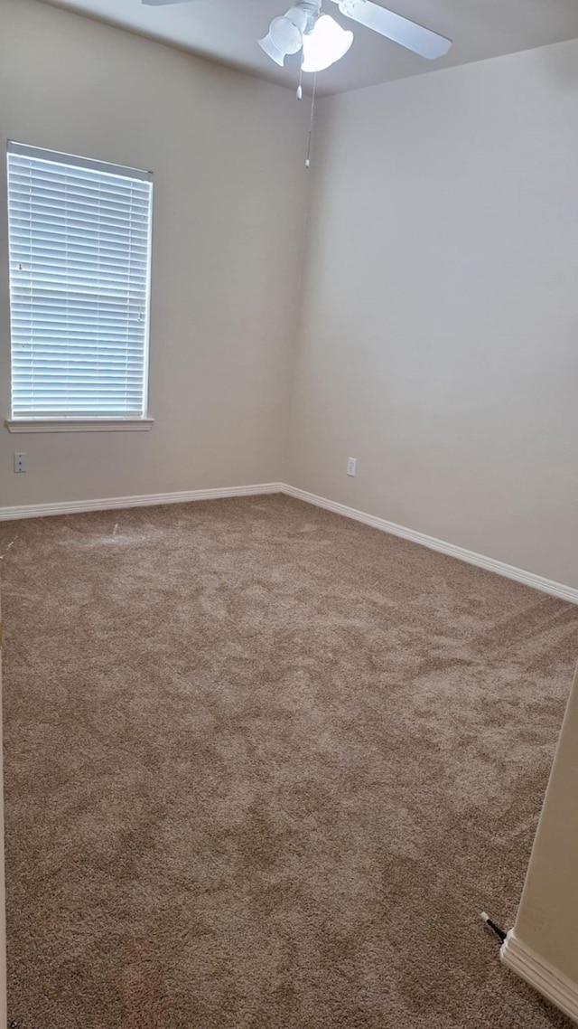 unfurnished room featuring a ceiling fan, carpet, and baseboards