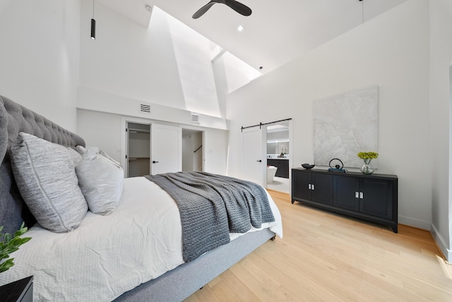 2135 Quenby St, Houston, TX 77005 - bedroom with a high ceiling, light wood-style flooring, baseboards, a barn door, and a ceiling fan