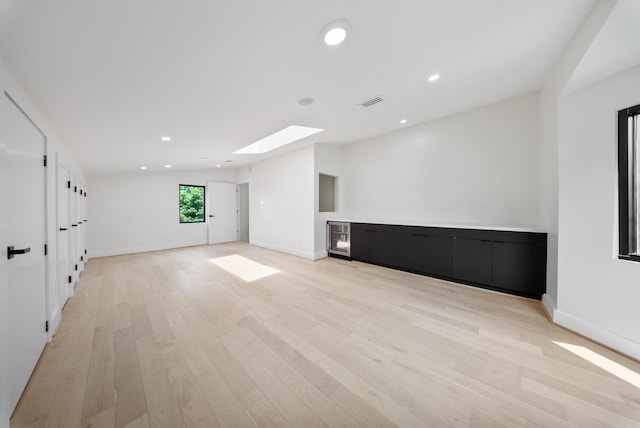 2135 Quenby St, Houston, TX 77005 - unfurnished living room with a skylight, wine cooler, light wood-type flooring, baseboards, and recessed lighting