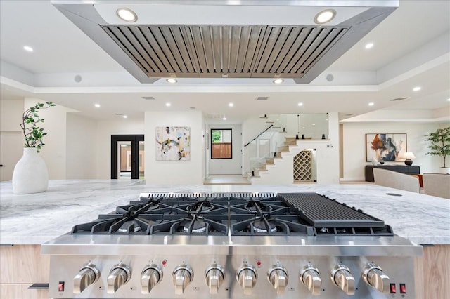2135 Quenby St, Houston, TX 77005 - kitchen view of stainless steel cooktop, wall chimney range hood, recessed lighting, and stone counters