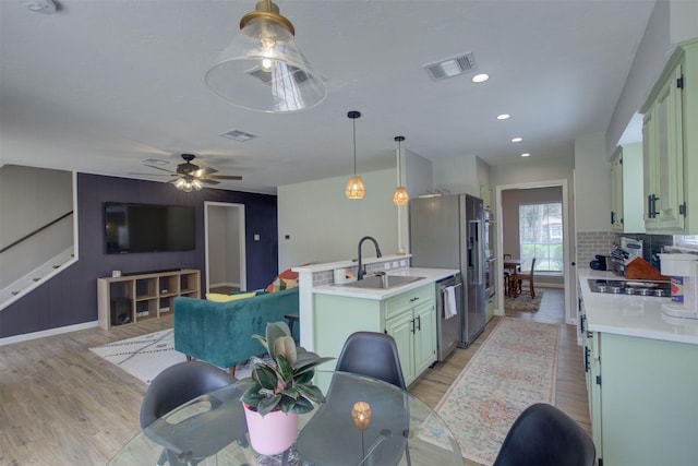 6019 Lawn Ln, Houston, TX 77088 - kitchen featuring stainless steel appliances, light wood-style flooring, light countertops, green cabinets, and tasteful backsplash
