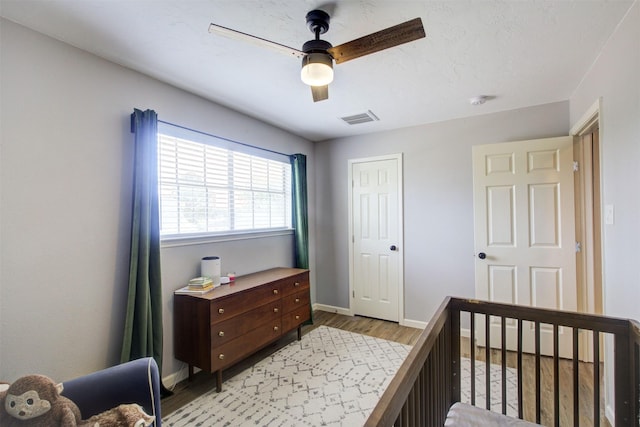 6019 Lawn Ln, Houston, TX 77088 - bedroom featuring light wood-type flooring, a ceiling fan, a crib, and a closet