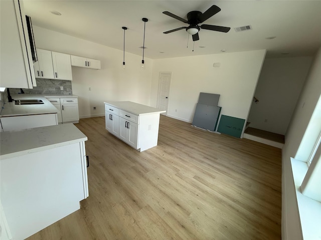 8605 Wileyvale Rd, Houston, TX 77016 - kitchen featuring ceiling fan, a sink, light wood-type flooring, decorative backsplash, and white cabinets