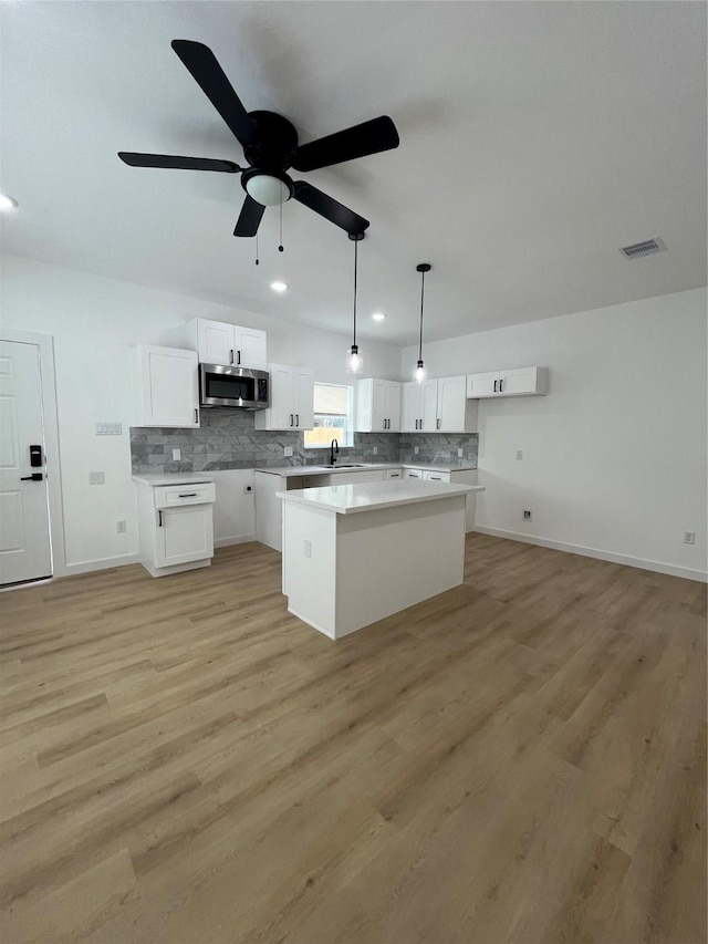 8605 Wileyvale Rd, Houston, TX 77016 - kitchen featuring stainless steel microwave, tasteful backsplash, white cabinets, a sink, and recessed lighting