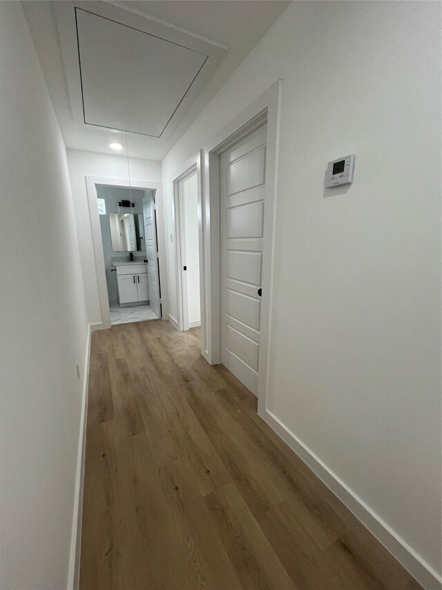 8605 Wileyvale Rd, Houston, TX 77016 - corridor featuring attic access, light wood-style flooring, and baseboards