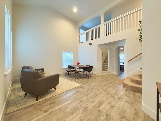 1404 Laguna Cv, Hutto, TX 78634 - living area featuring stairway, light wood-style flooring, healthy amount of natural light, high vaulted ceiling, and arched walkways